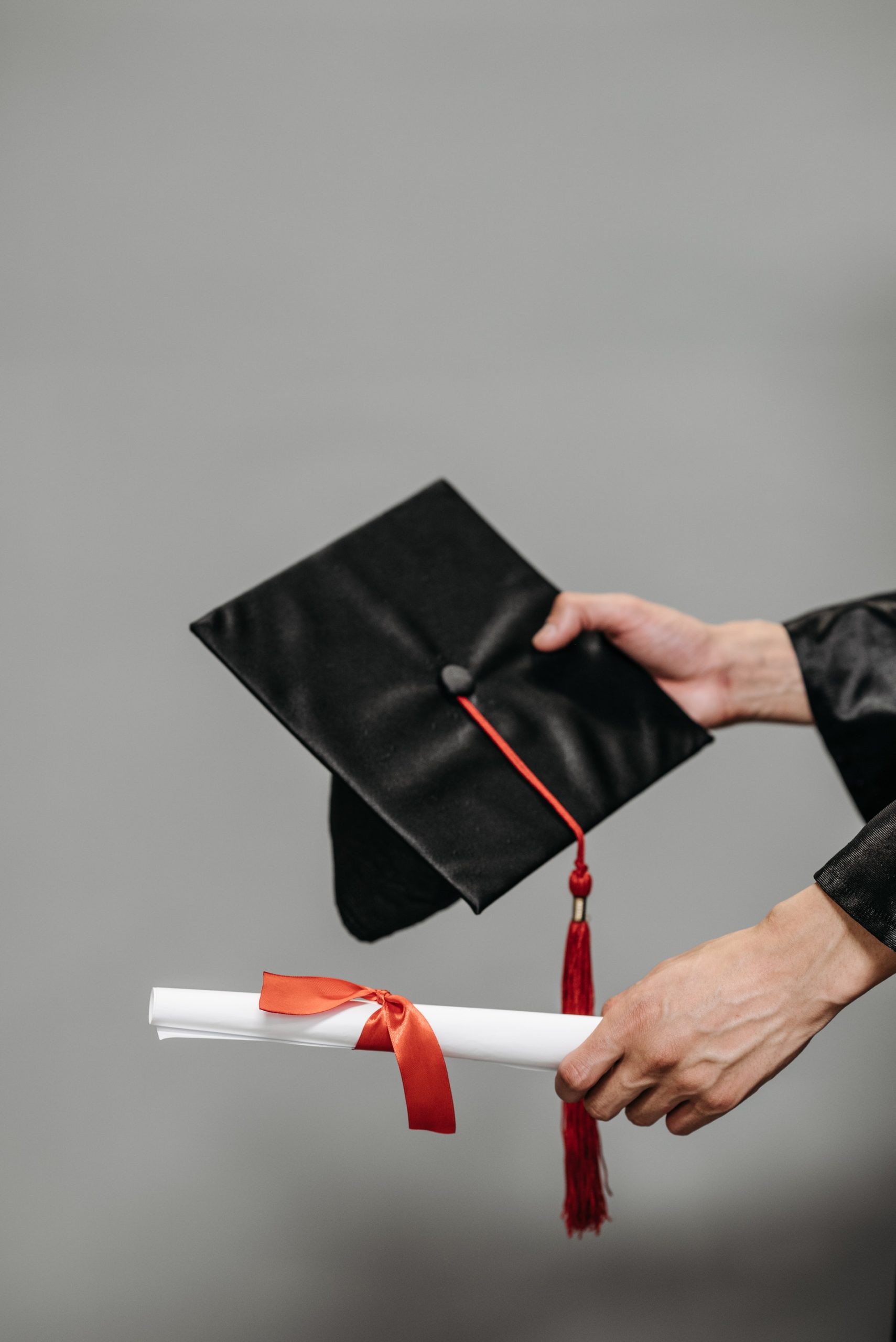 A hand holding a fake bachelor degree diploma template and cap